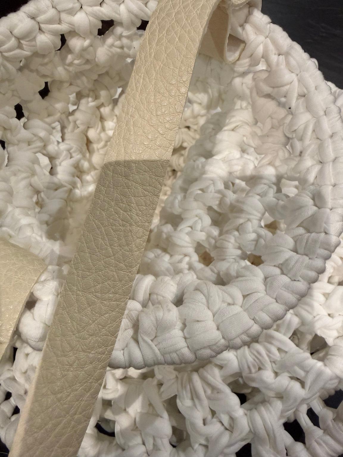 Detail van het lederen hengsel en het witte haakwerk