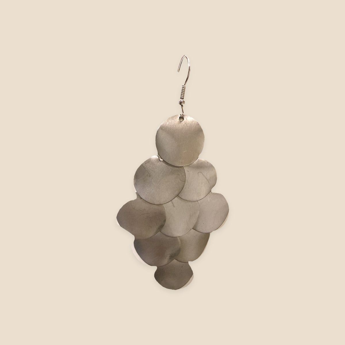 Silver Cascade zilverkleurige oorbel met overlappende ronde schijfjes op warm beige